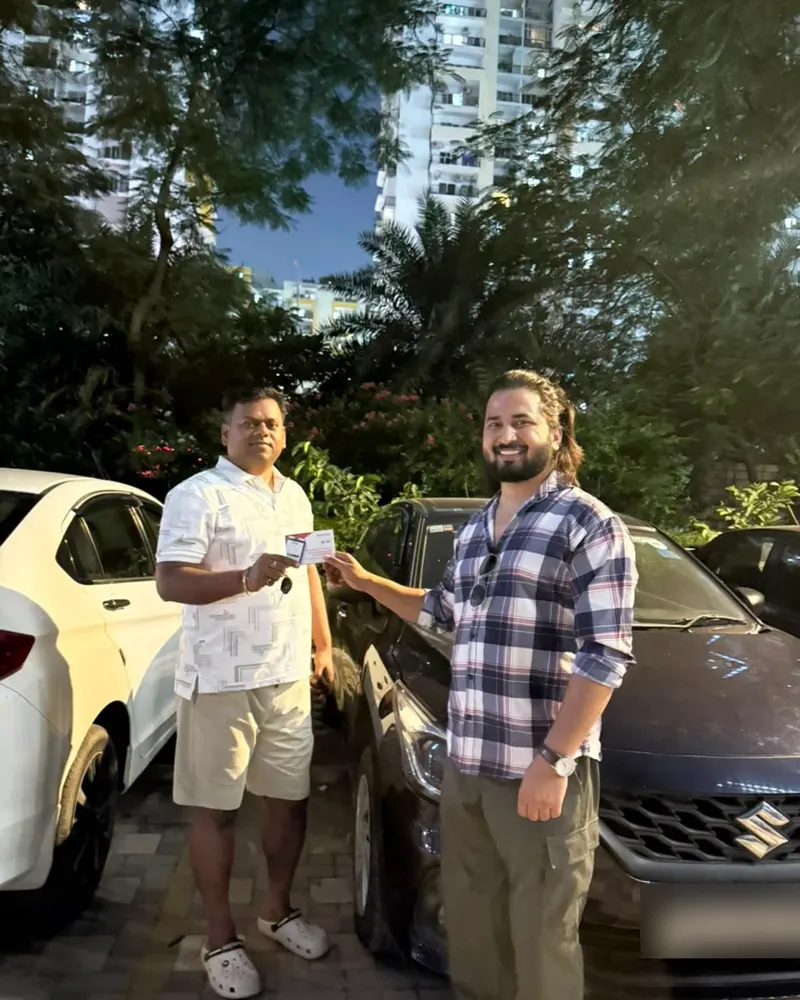 A ParkTag being handed to customer Shivam beside his car